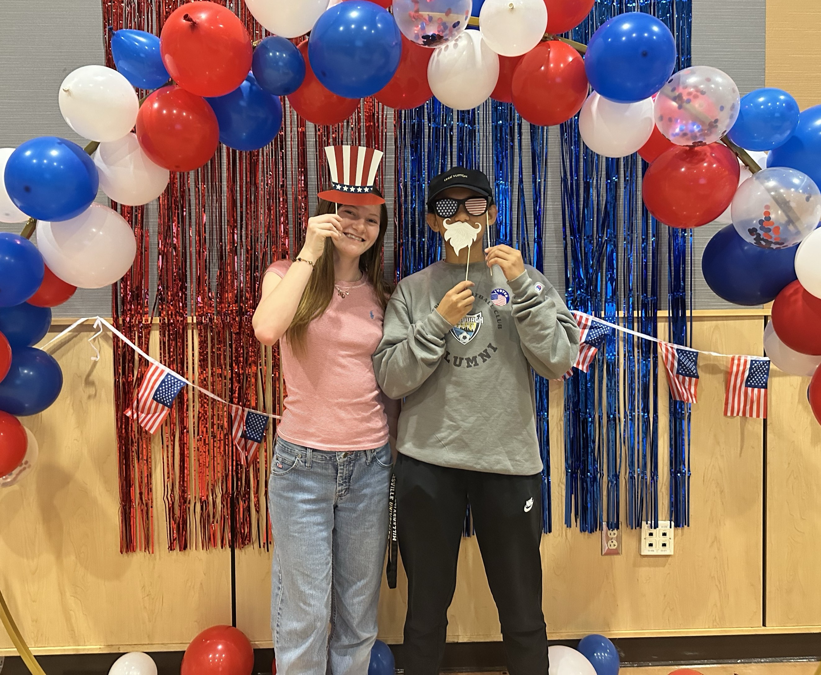 Two students under the balloon arch selfie station