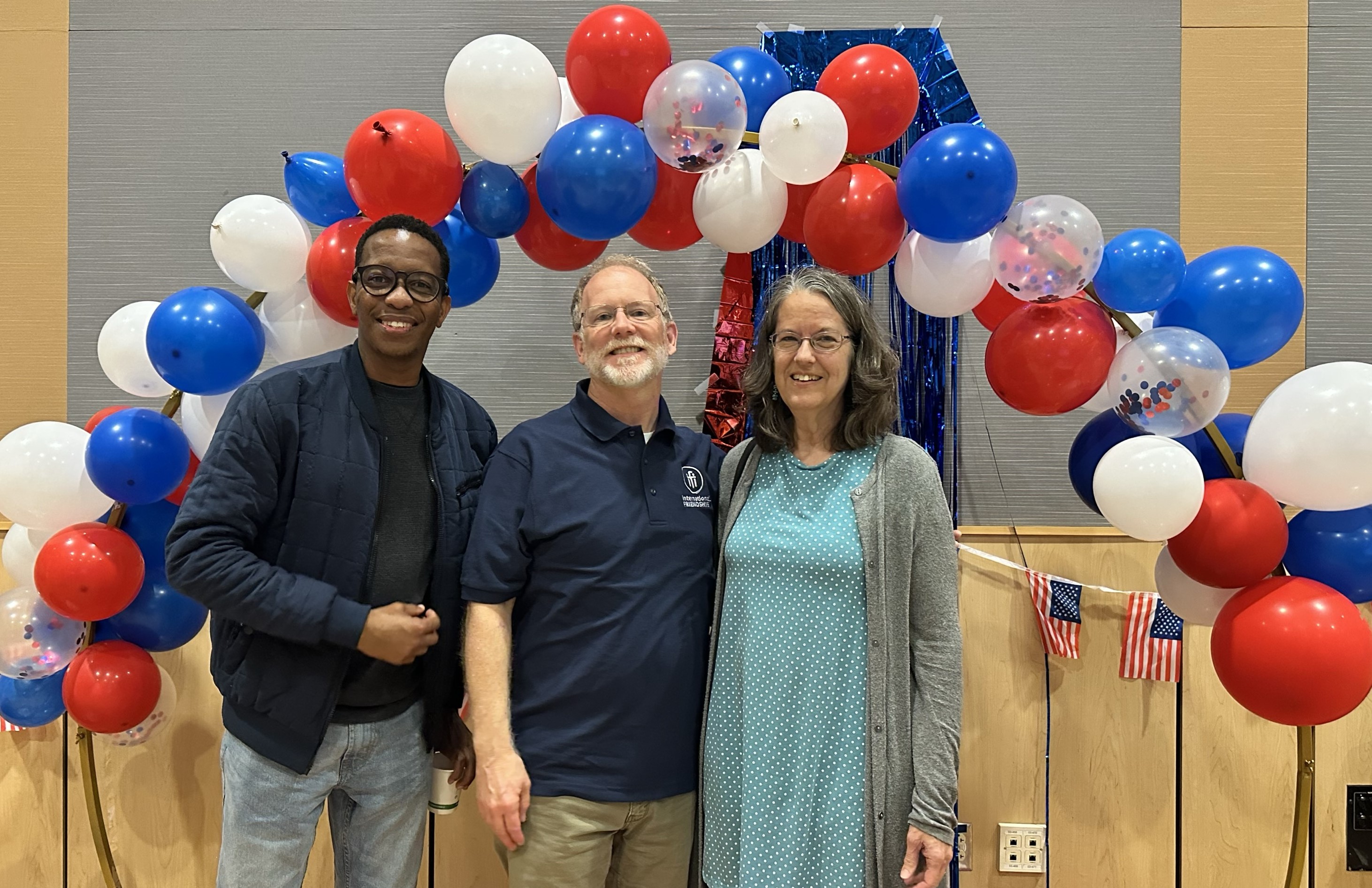 Three people under balloon arch selfie station