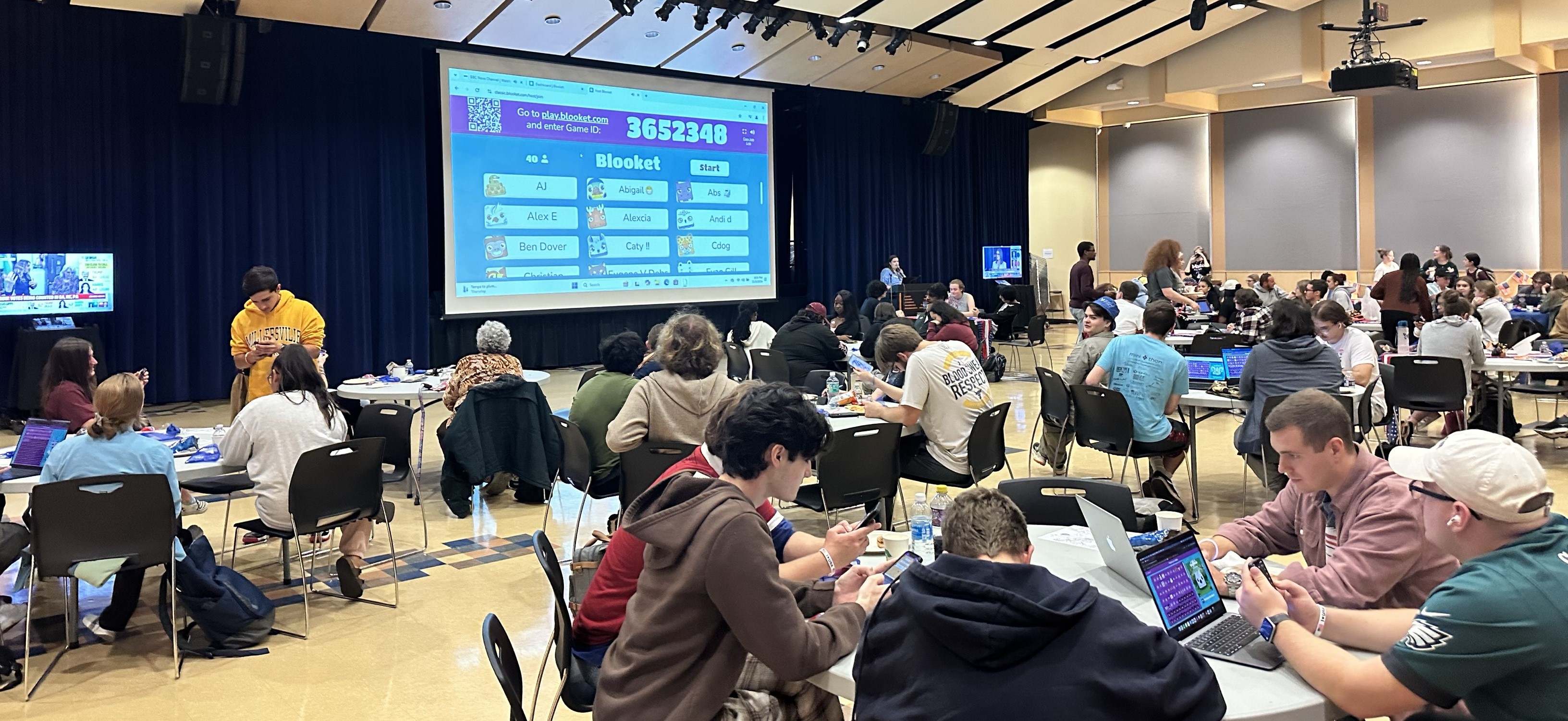 Wide shot of SMC MPR with students sitting at tables watching the projector for Blooket