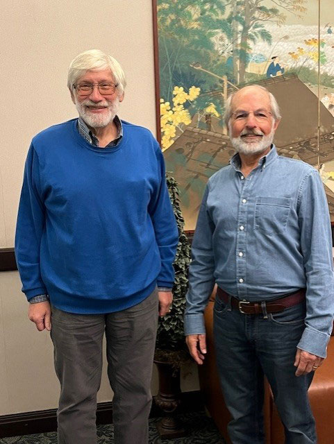 two retired men smiling at the camera