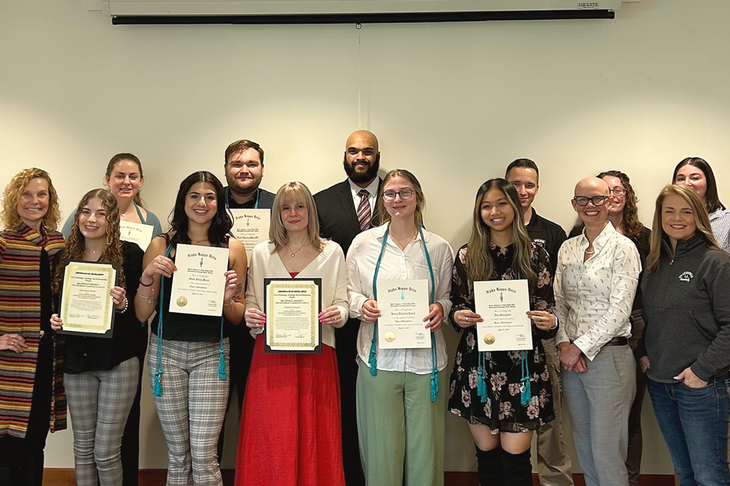 AKD honor society inductees and alumni guest speakers stand with certificates